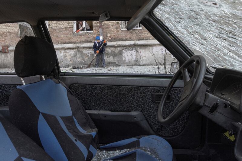 Locals clean the area at a residential district of Kyiv that was damaged by shelling, as Russia’s invasion of Ukraine continues. Reuters