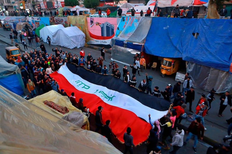 Anti-government protesters chant slogans while holding the national flags during a demonstration against the newly-appointed Prime Minister Mohammed Allawi in Tahrir Square, Baghdad. AP Photo