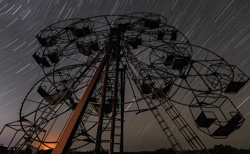 This long-exposure picture taken shows a view of star trails along the celestial equator behind a children's ride at an abandoned amusement park near al-Nayrab, a village ravaged by pro-government forces bombardment, in Syria's northwestern Idlib province.  AFP