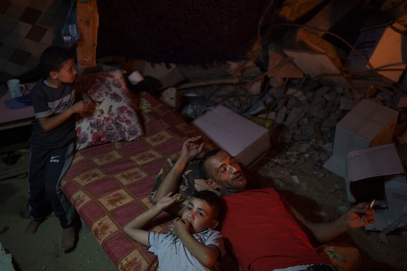 Family members lie inside a makeshift tent built on the rubble of their home, destroyed by an air strike in Beit Lahia, northern Gaza Strip. AP