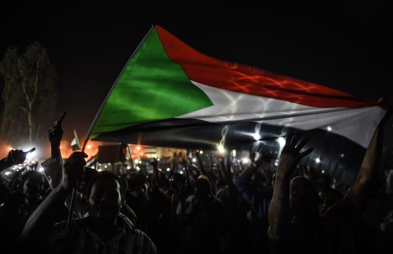 Sudanese protesters are wawing flags during a sit-in outside military headquarters after clashing with security forces in Khartoum on May 15, 2019.

 Violent clashes erupted in the capital, Khartoum, for the second time this week. / AFP / Mohamed el-Shahed

