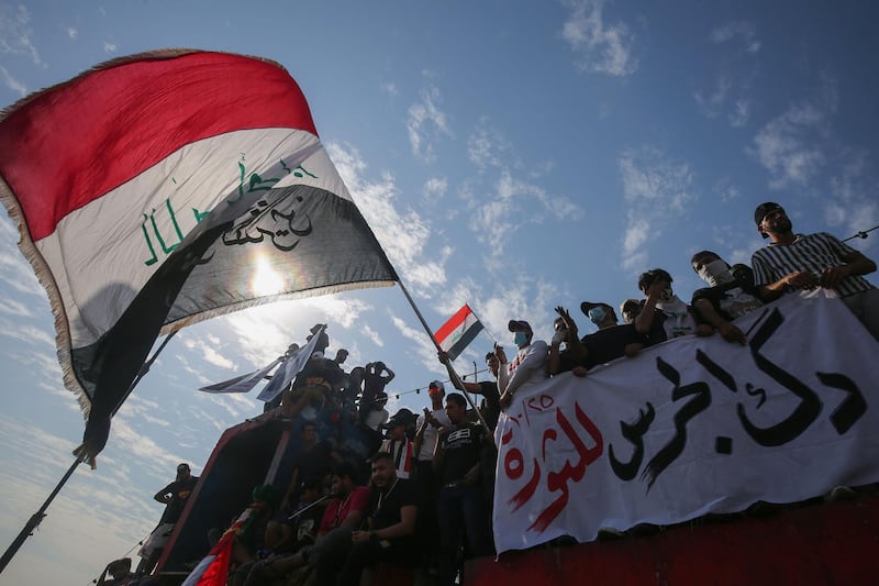 Iraqi demonstrators wave flags as they gather in Tahrir Square in the centre of the capital Baghdad to mark the first anniversary of a massive anti-government movement demanding the ouster of the entire ruling class accused of corruption. AFP