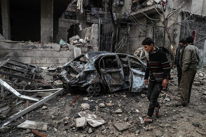 This photo, taken on January 6, 2016, shows a boy walking past a destroyed car in Eastern Ghouta's Hammuriyeh, where at least 12 civilians were killed. Mohammed Badra / EPA