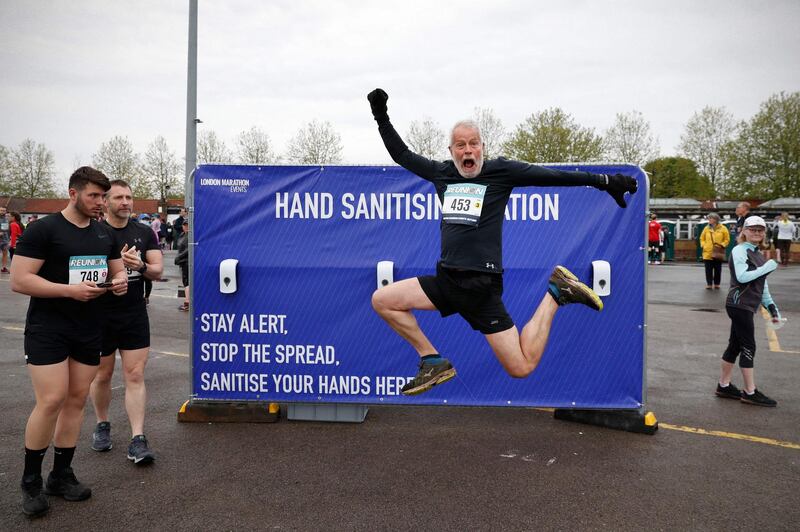 A competitor leaps in front of a hand sanitiser station ahead of the socially-distanced Reunion 5K race at Kempton Park, Surrey, England. AFP