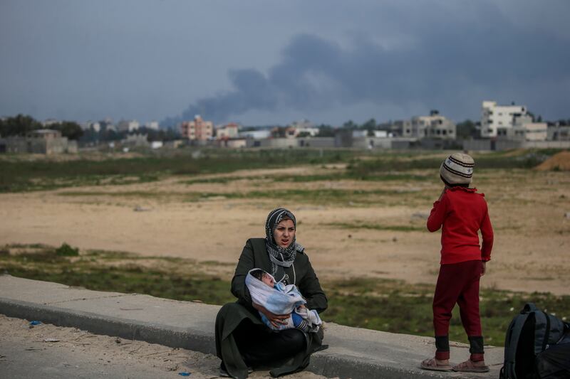 A Palestinian mother takes a rest after crossing from the northern Gaza Strip to the south along Al Rashid road this week.  EPA