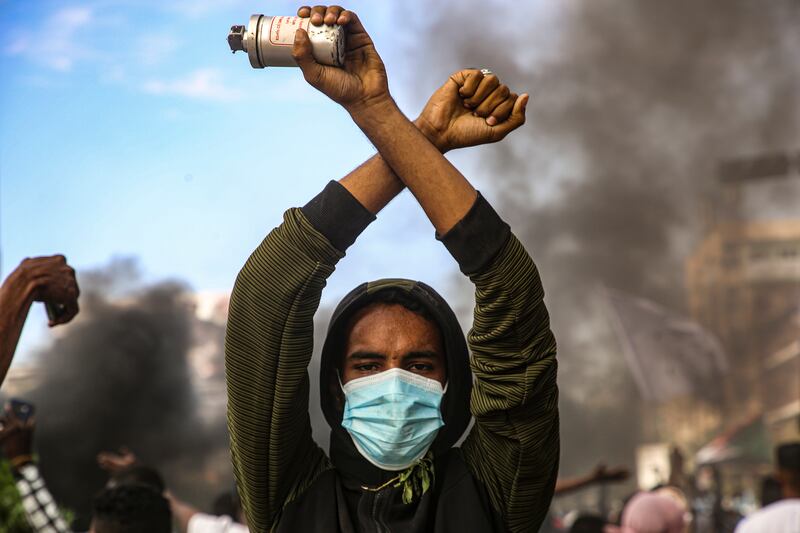 A Sudanese protester carries a canister during a protest near the presidential palace in the capital Khartoum on Saturday. Tens of thousands of people took to the streets in the capital and other cities to demonstrate against a deal reinstating Prime Minister Abdalla Hamdok after his ousting in a military coup on October.  EPA