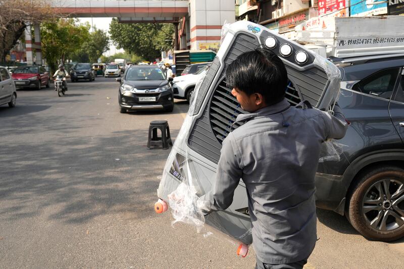 A man carries a water cooler for his home as temperatures rise in New Delhi. AP