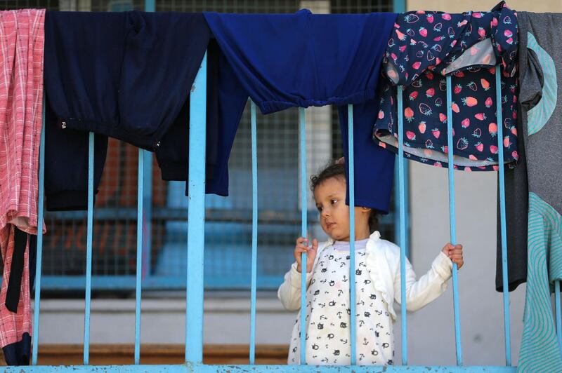 A Palestinian girl, who fled her family's home due to Israeli air and artillery strikes, looks through a railing at a UN-run school  in Gaza city. Reuters