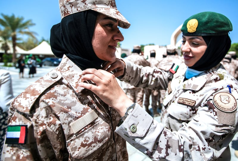 Naeema Alblalooshi, left, a police officer from Bahrain is assisted by a colleague before a group photo. 
