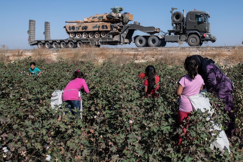 Turkish military vehicles carrying tanks head to the Syrian border as farmers work in a cotton field in Akcakale, Turkey. The military action is part of a campaign to extend Turkish control of more of northern Syria, a large swath of which is currently held by Syrian Kurds, whom Turkey regards as a threat. U.S. President Donald Trump granted tacit American approval to this campaign, withdrawing his country's troops from several Syrian outposts near the Turkish border. Getty Images