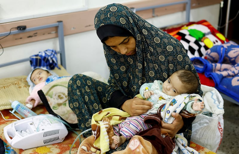 Wafaa Tabasi with her twin malnourished daughters, at Al Awda health centre in Rafah, in March. Reuters