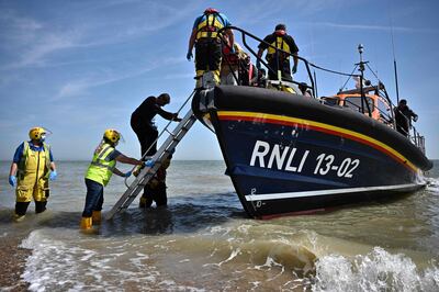 British lifeguards help migrants off a boat after they were picked up while trying to cross the English Channel. AFP 