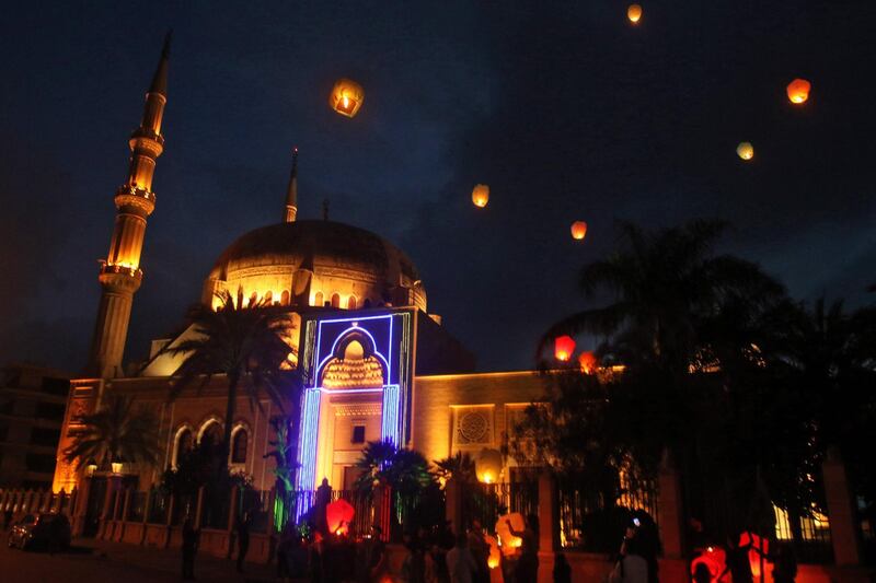 TOPSHOT - People release sky lanterns as they celebrate the start of the Muslim holy month of Ramadan, outside a mosque in Lebanon's southern city of Sidon after sunset on April 23, 2020.  / AFP / Mahmoud ZAYYAT
