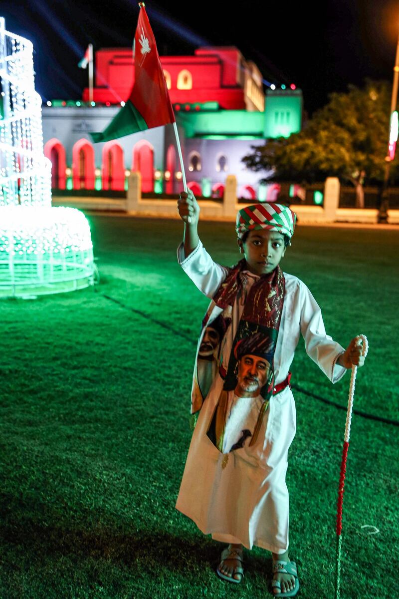 An Omani child wearing a scarf featuring Oman's Sultan Haitham, right, and his predecessor the late Sultan Qaboos, celebrates near the Royal Opera House Muscat. AFP