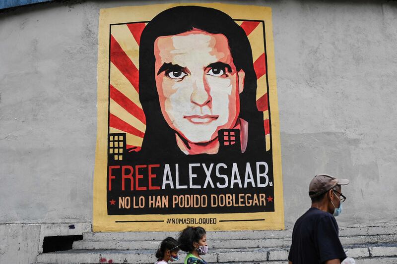 People walk past a poster with the image of Colombian businessman Alex Saab, demanding his release, in Venezuela's capital Caracas. Photo: AFP