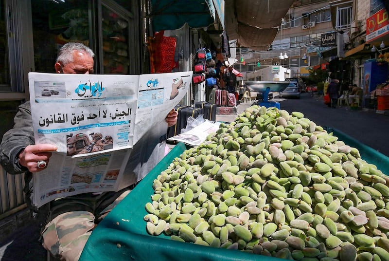 A Jordanian street vendor reads a local newspaper with a headline on its front page about the latest events in his country, in the capital Amman, on April 4, 2021. Jordan's official media warned today that security and stability are a "red line", a day after several senior figures were detained and a half-brother of King Abdullah II said he was put under house arrest. / AFP / Khalil MAZRAAWI
