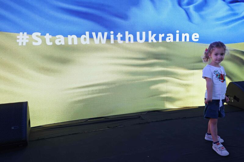 A girl poses for a picture with a screen displaying support for Ukraine. AFP