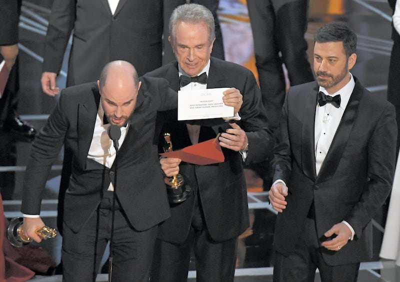 "La La Land" producer Jordan Horowitz (L) shows the card saying "Moonlight" won the best picture as actor Warren Beatty  (C), and Host Jimmy Kimmel look on at the 89th Oscars on February 26, 2017 in Hollywood, California. (Photo by Mark RALSTON / AFP)