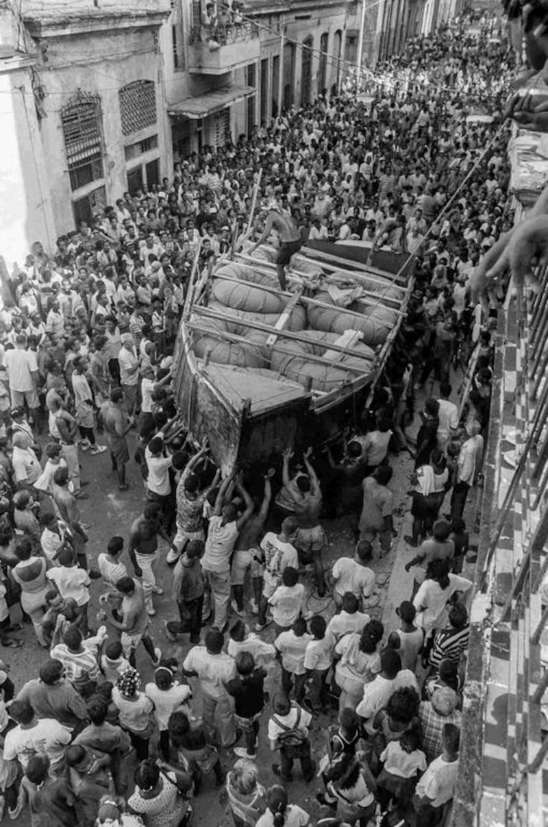 Cubans watch as a makeshift boat is carried to the sea.