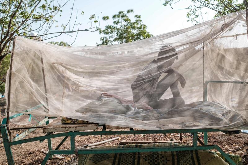 A civilian man fleeing violence seats in a bed covered with a mosquito net in the city of Semera, Ethiopia. AFP