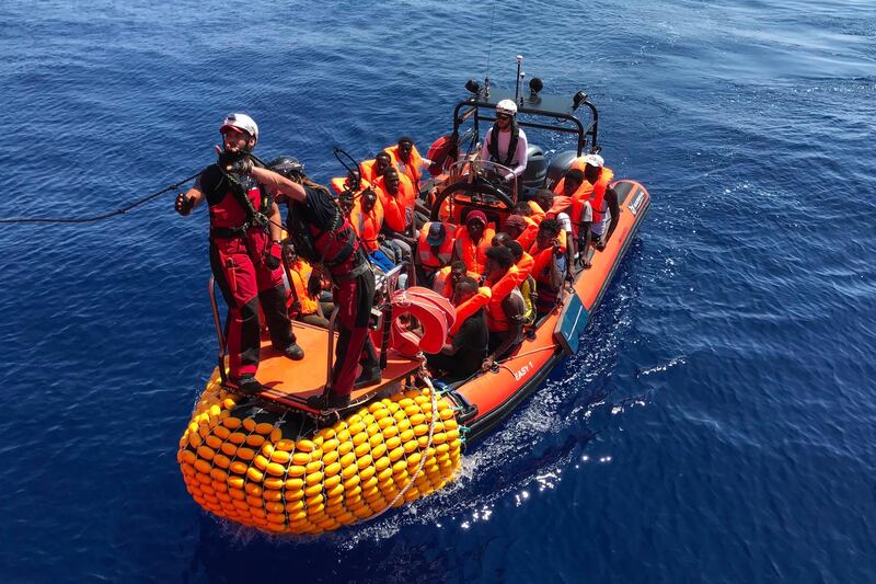 A "rhib", an inflatable dinghy, belonging to the 'Ocean Viking' rescue ship, operated by French NGOs SOS Mediterranee and Medecins sans Frontieres (MSF), transports migrants rescued from their dinghy during an operation in the Mediterranean Sea on August 12, 2019. The rescue operation comes as a dispute escalates over which countries will take in migrants rescued by different charity ship operating in the area, as mild Mediterranean weather increases the number of people trying to make their way to Europe from Africa. / AFP / Anne CHAON
