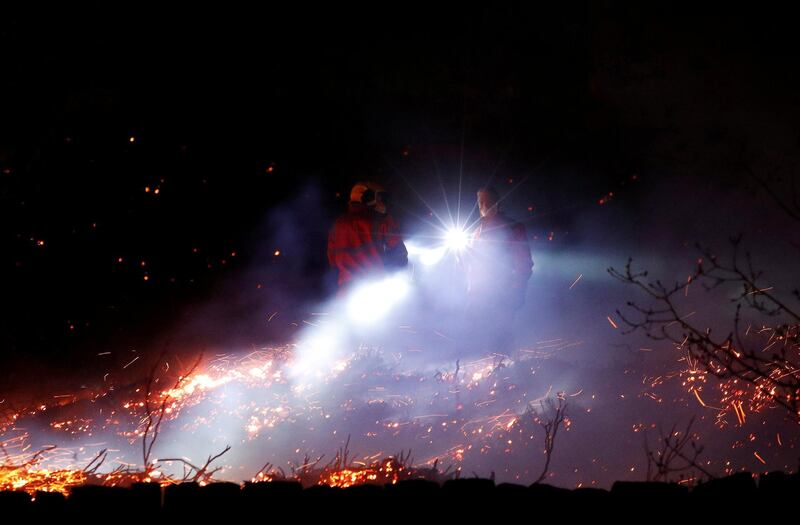Firefighters tackle a fire on a patch of moorland above the village of Uppermill, Britain.  Reuters