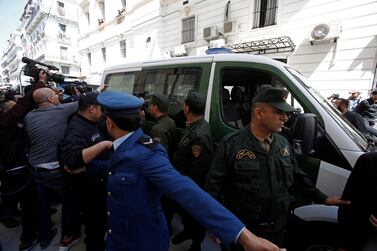 Media and police surround a convoy of police vehicles as businessmen suspected of corruption are driven to court in Algiers. Reuters