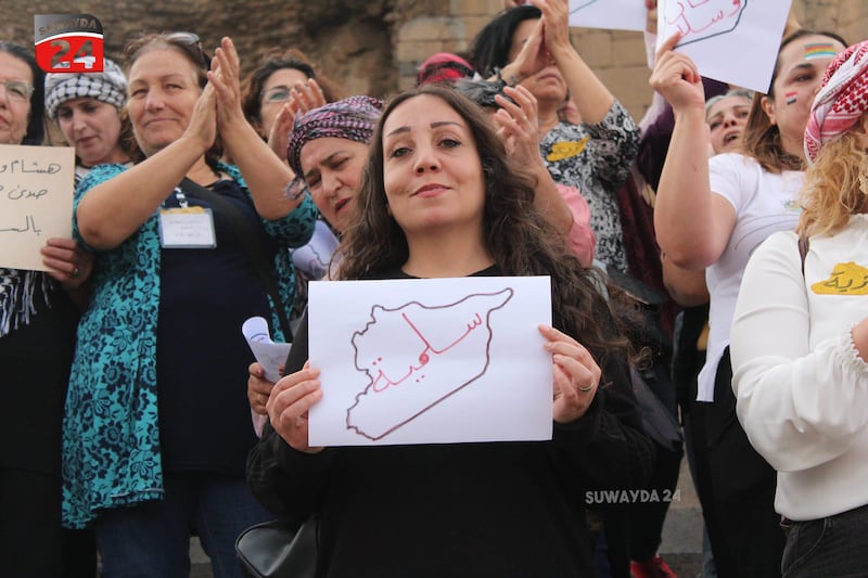 A demonstrator carrying a placard with a map of Syria and the word 'peaceful', at a pro-democracy demonstration in Suweida. Photo: Suwyada 24