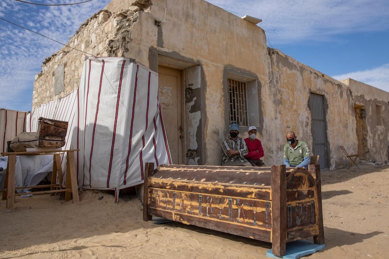 Workers rest near a trove of ancient artifacts on display that Egyptian archaeologist Zahi Hawass and his team unearthed in a vast necropolis filled with burial shafts, coffins and mummies dating back to the New Kingdom 3000 BC in Saqqara, south of Cairo, Egypt. AP