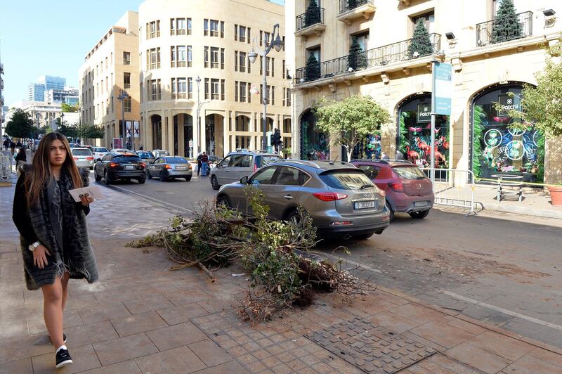 epa08075249 A woman walks next to a damaged tree after overnight violent clashes between anti-government protesters and security forces in front of Nijmeh Square, the seat of the Lebanese Parliament, in downtown Beirut, Lebanon, 16 December 2019. Lebanese President Michel Aoun for the second time on 16 December postponed parliamentary consultations until 19 December to name the next Prime Minister.  EPA/WAEL HAMZEH