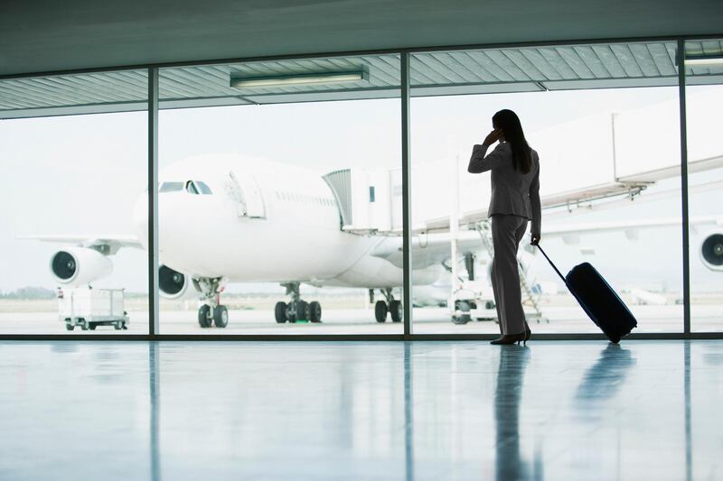 Businesswoman with suitcase in airport. Getty Images