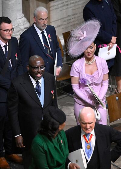 Edward Enninful wears a blue waistcoat with his suit, while Katy Perry wears all pink. AP