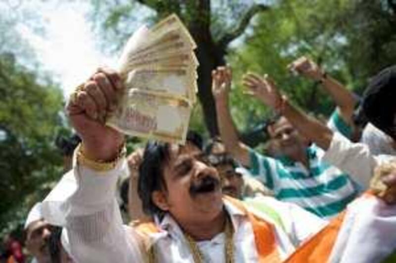 NEW DELHI, INDIA - MAY 16: A man holds money as supporters celebrate election results in front of the headquarters of the Congress Party  on May 16, 2009 in New Delhi, India. Senior BJP leader Arun Jaitley has admitted defeat in the Indian general election. Televison networks are reporting that India's Prime Minister Manmohan Singh's Congress Party appear to be heading for a victory as votes were counted on Saturday. (Photo by Keith Bedford/Getty Images) *** Local Caption ***  GYI0057453657.jpg