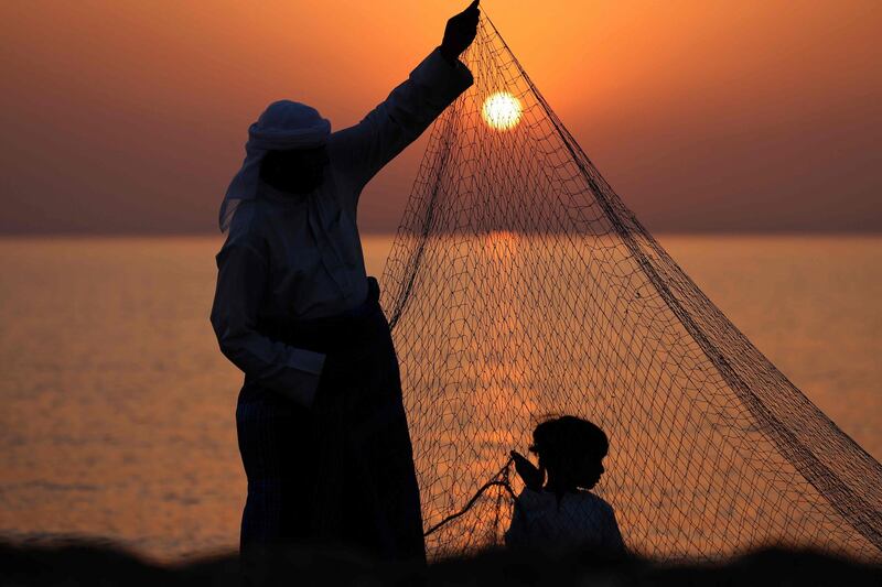 An Emirati fisherman helped by a child sets up nets on the shore of Dalma island in the Arabian Gulf, near Abu Dhabi. AFP