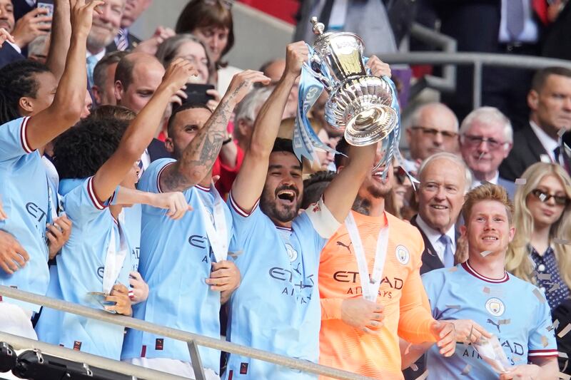 Manchester City's Ilkay Gundogan, centre, holds up the winners' trophy after the FA Cup final win over Manchester United at Wembley on Saturday, June 3, 2023. AP