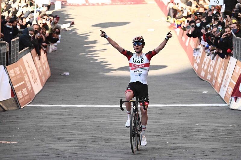 Tadej Pogacar celebrates as he crosses the finish line to win the Strade Bianche. AFP