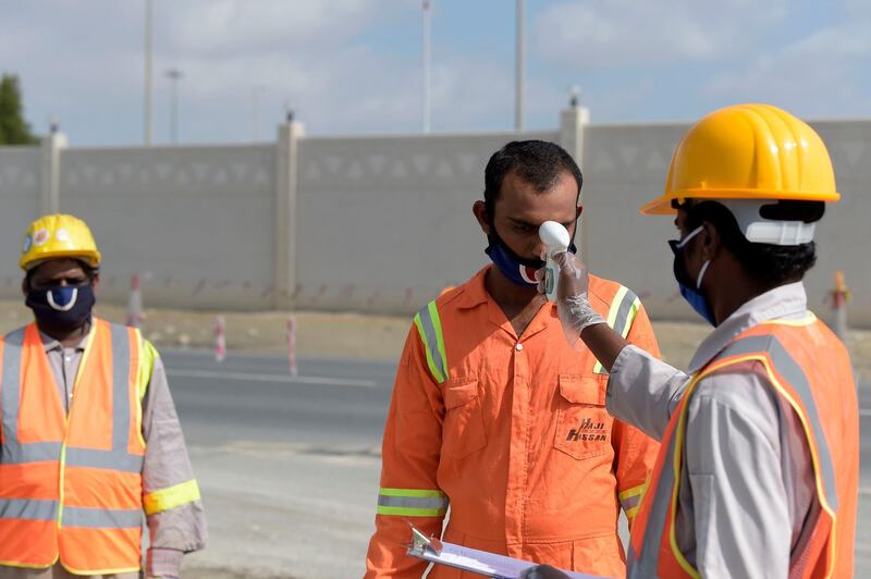 Expatriated workers have their temperatures checked while carrying out road project development in Aali village south of the Bahraini capital. AFP