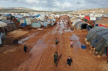 Syrian refugees walk through a camp for displaced muddied by recent rains near the village of Kafr Aruq , in Idlib province, Syria. AP