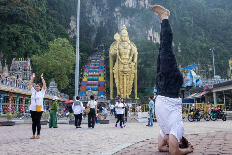 A yoga practitioner performs a headstand in front of Batu Caves in Gombak, Malaysia. Getty Images