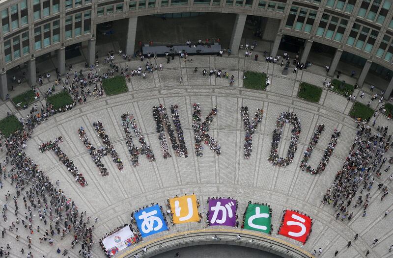 TOPSHOTS - People spell out the words "THANK YOU" at the Tokyo metropolitan government building on September 8, 2013, after Tokyo's won its bid to be the host city of the 2020 Olympics. Tokyo won the right to host the Olympic Games for the second time, overcoming fears about radiation from the stricken Fukushima nuclear plant to land the 2020 edition of the world's biggest sporting event.     JAPAN OUT   TOPSHOTS   AFP PHOTO / JIJI PRESS
 *** Local Caption ***  894773-01-08.jpg