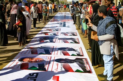 Sudanese demonstrators in Khartoum standing around a banner bearing images of protesters killed by security forces since last year's military coup. AFP