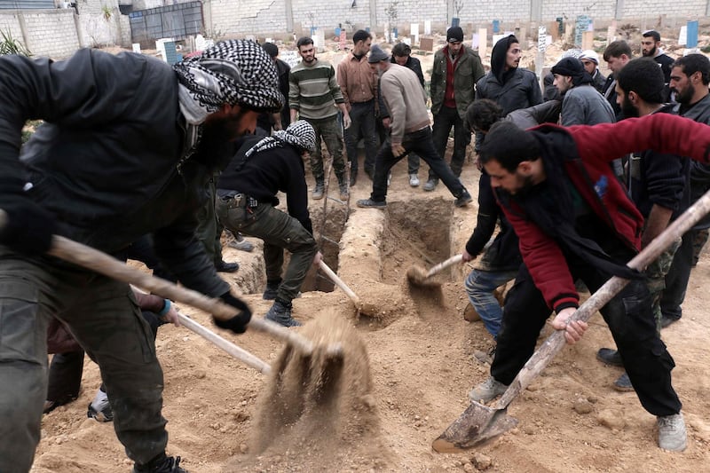 Syrians bury bodies during a group funeral ceremony at a cemetery following reported airstrikes on January 7, 2016 in the rebel-held city of Douma, northeast of the capital Damascus. More than 260,000 people have been killed since the Syrian conflict erupted in March 2011 and millions forced from their homes. (Photo by AMER ALMOHIBANY / AFP)