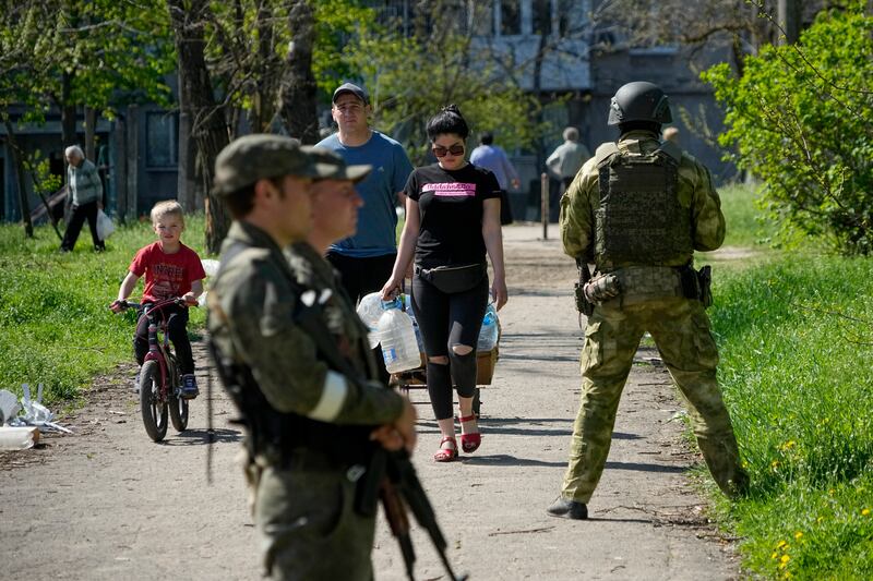 Members of the pro-Russia Donetsk People's Republic militia stand guard as civilians go to receive aid in Mariupol. AP
