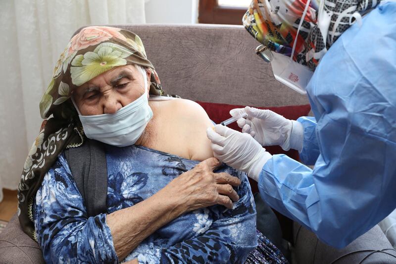 In this photo provided by Turkey's Health Ministry, a vaccination team member administers a dose of the CoronaVac vaccine, produced by China's Sinovac Biotech Ltd., to Sati Kayiran, 88, in Ayas, in Ankara province, Turkey, Thursday, Jan. 21, 2021. Turkey on Thursday expanded its COVID-19 inoculation campaign to include people aged 85 and older. (Turkish Health Ministry via AP)