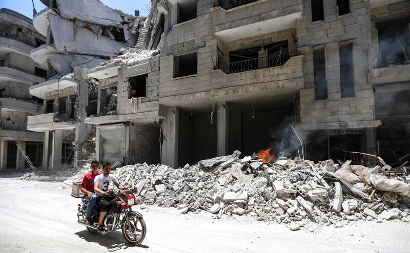 Men ride a motorcycle past debris outside a hospital hit  in an  air strike in Jisr Al Shughur in the northeastern Syrian Idlib province.  AFP