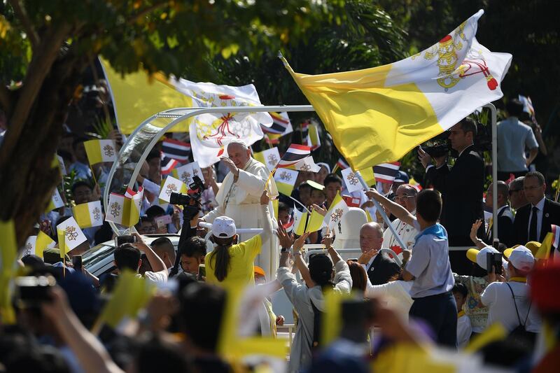 Faithful wave Vatican flags as Pope Francis arrives at St. Peter's Parish in Bangkok, Thailand. AFP