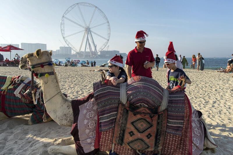 Dubai, United Arab Emirates, December 25, 2017:    American expatriates Matt Hubbard with his children Olivia, 8, left and Gage,10, with a camel on Jumeirah Beach Residence on Christmas Day in the Dubai Marina area of Dubai on December 25, 2017. Christopher Pike / The National

Reporter:  N/A
Section: News