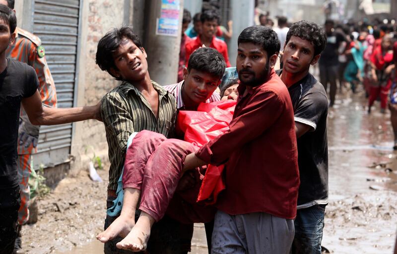 epa03674822 Civilians rescue an injured garment worker during a rescue operation after the eight-storey Rana Plaza building collapsed at Savar in Dhaka, Bangladesh, 24 April 2013. At least 20 people died including garment workers and many more were critically injured, reports said.  EPA/ABIR ABDULLAH *** Local Caption ***  03674822.jpg