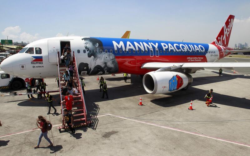 Passengers disembark the AirAsia Philippines Airbus A320 plastered with the image of Filipino boxer Manny Pacquiao as they arrive from Cebu at the domestic airport in Pasay city, metro Manila Apiril 28, 2015. AirAsia Philippines show their support to Pacquiao by painting their aircraft with the boxing icon's name and face, an AirAsia official said. Pacquiao is set to fight American boxer Floyd Mayweather Jr. on May 2 at Las Vegas, Nevada.     REUTERS/Romeo Ranoco