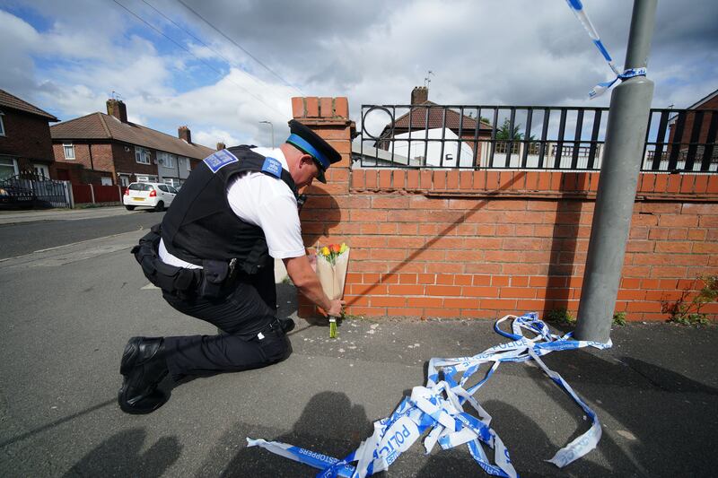 On Tuesday a police officer lays flowers near the scene where Olivia Pratt-Korbel, 9, was fatally shot, on Kingsheath Avenue in Knotty Ash, Liverpool. PA